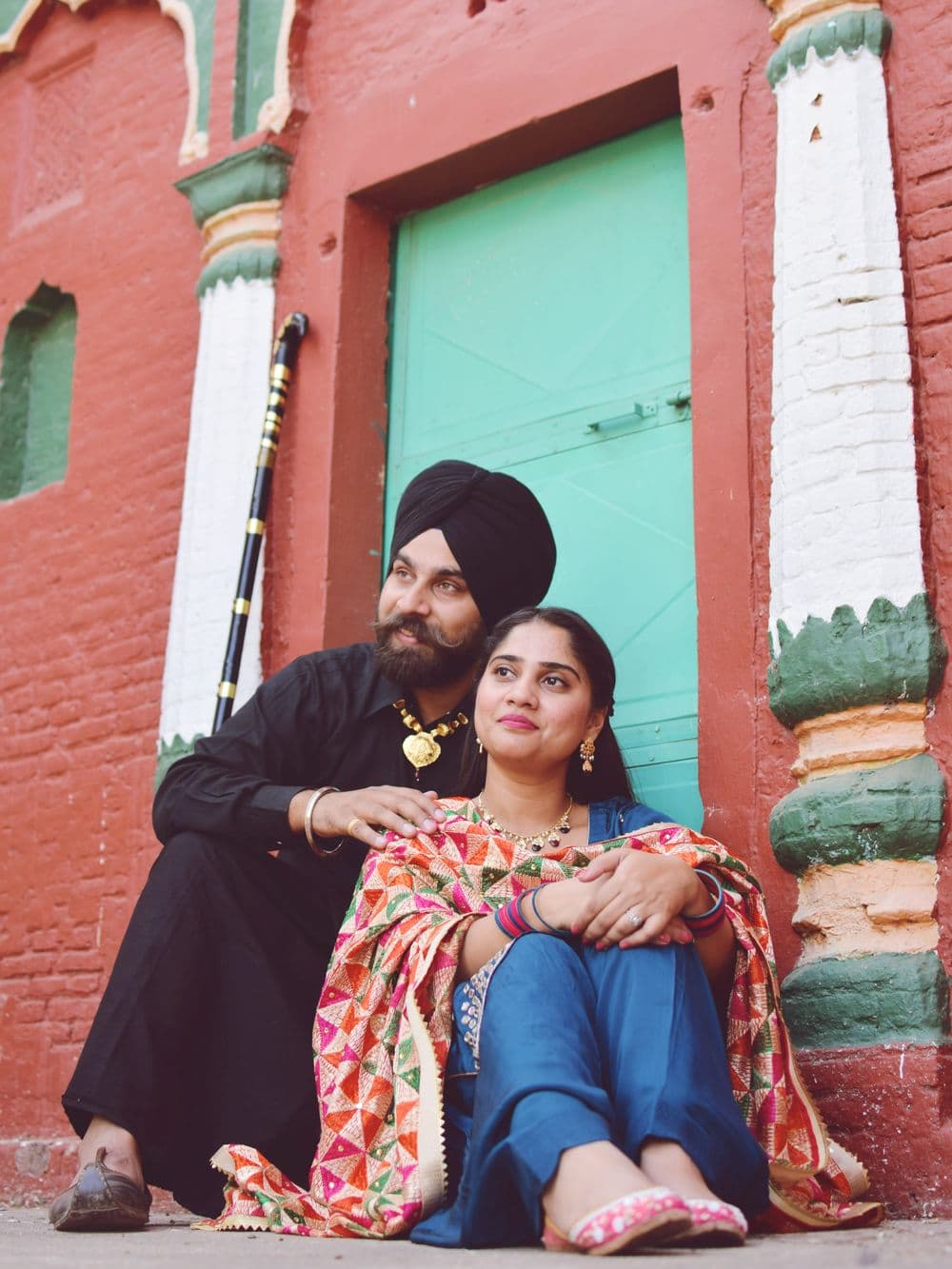 A couple sitting together outside a brightly painted house
