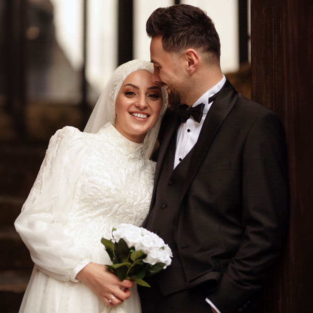 A bride in a white dress and veil beside her groom