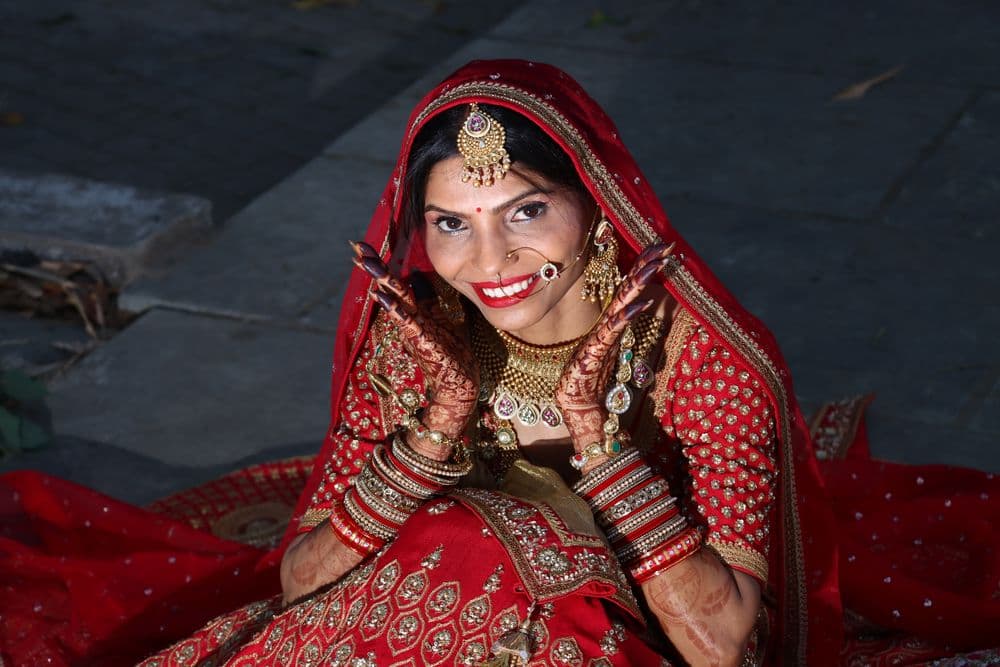 A bride in a red wedding sari and gold jewellery